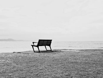 Empty chair on beach against sky