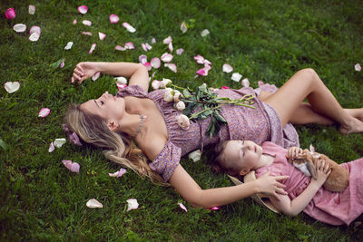 Portrait of a beautiful mother and her baby daughter lying on a green meadow in summer 