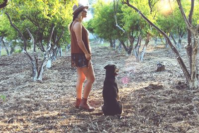 Full length of woman standing with dog on field