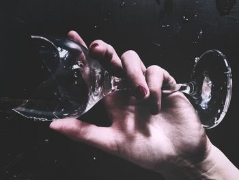 Close-up of hand holding water against black background