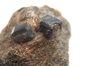 Close-up of rusty metal on rock against white background