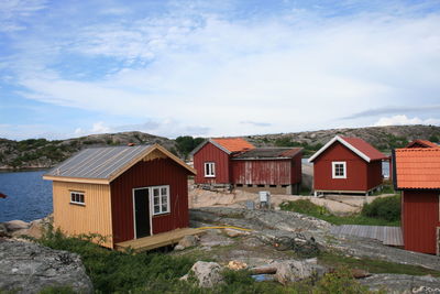 Log cabins by lake against sky