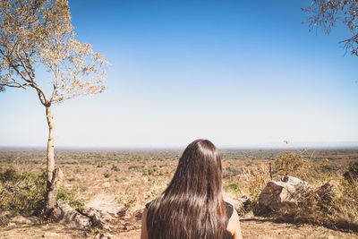 Rear view of woman looking at landscape against clear sky