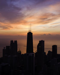 Silhouette modern buildings in city against sky during sunset