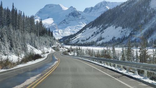 Road by snowcapped mountains during winter