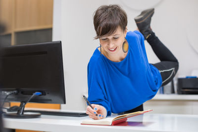 Young woman taking notes and stretching in the office