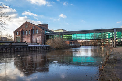 Buildings by lake against sky