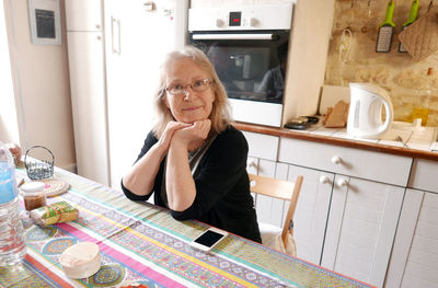 Portrait of smiling mature woman sitting on chair at home