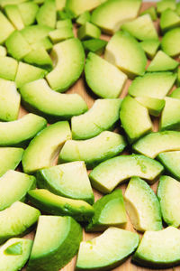 Sliced avocado into small pieces lie on a cutting wooden board. copy space