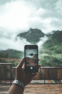 Midsection of person photographing with smart phone against sky