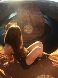 High angle view of woman sitting on cliff at horseshoe bend