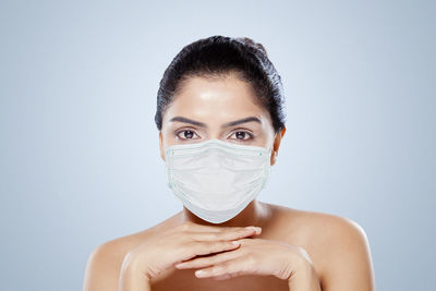 Portrait of beautiful woman wearing mask against colored background