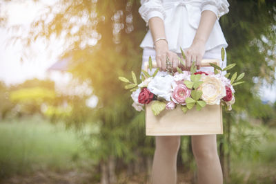 Midsection of woman holding flower on field