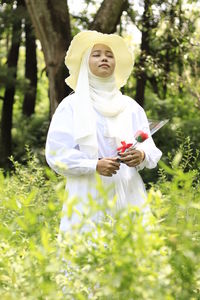 Woman standing on field against trees