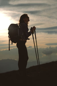 Silhouette woman hiking on mountain against sky during sunset