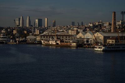 Sea by buildings in city against sky