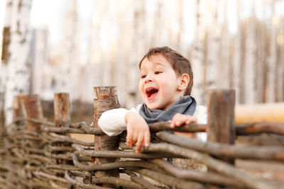 Portrait of boy looking away and standing near the fence 
