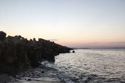 Stack of rocks on beach against sky during sunset