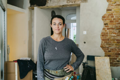 Portrait of confident female construction manager standing with hand on hip at construction site