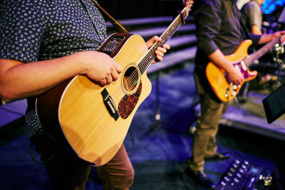 Midsection of musicians playing guitar on stage