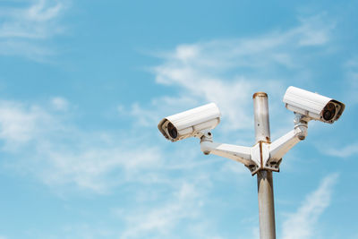 Low angle view of security camera against sky