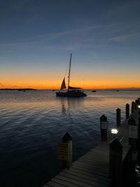 Silhouette sailboat in sea against sky during sunset