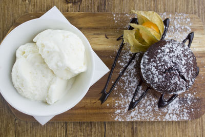 Petit gateau with ice cream and physalis on a wooden board. top view