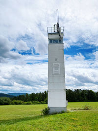 Lighthouse on field against sky