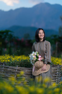 Portrait of a smiling young woman standing by plants on mountain