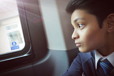 Thoughtful boy sitting by window in train