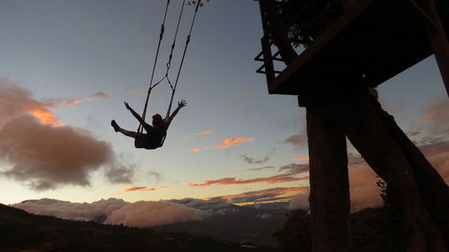 Low angle view of silhouette person paragliding against sky during sunset