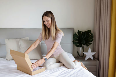 Young woman using laptop while sitting on bed at home