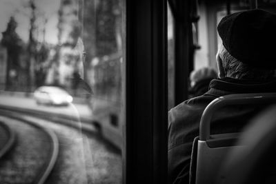 Rear view of man seen through train window