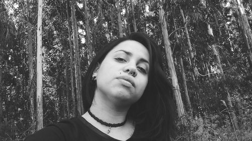 Portrait of young woman against trees at forest