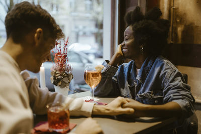 Boyfriend holding hand and flirting with girlfriend during date at restaurant