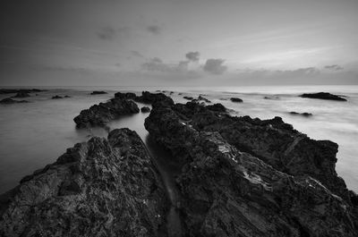 Rock formation on beach against sky