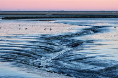 Scenic view of frozen landscape against sky during sunset