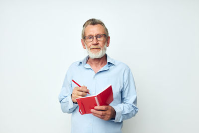 Portrait of young man holding paper currency against white background