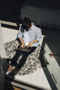 High angle view of female freelancer using laptop in bedroom at home