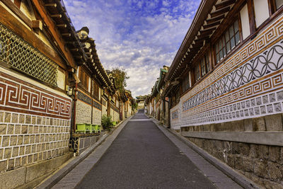 Empty road amidst buildings against sky