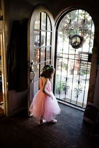 Young girl standing by front door wearing tutu and flower crown