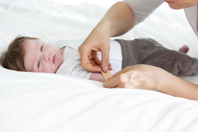 Cropped image of mother applying bandage on daughter hand at home