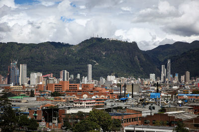 Aerial view of townscape by mountains against sky