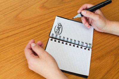 High angle view of person hand holding text on table