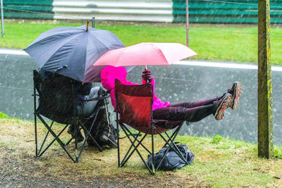 Midsection of person holding umbrella on field during rainy season