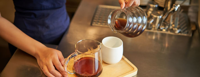 Midsection of woman holding coffee on table