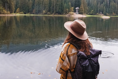 Calm mountain lake with beautiful reflection. young woman in hat in autumn mountains.