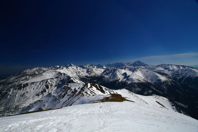 Scenic view of snowcapped mountains against blue sky