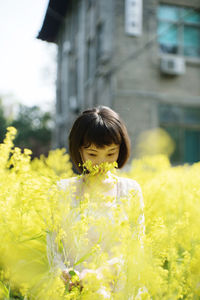 Portrait of woman standing on yellow flowering plants
