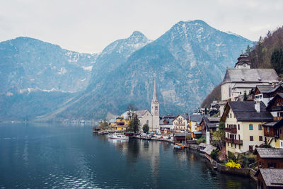 Picturesque landscape of traditional residential houses and famous lutheran parish church of hallstatt located on lake shore surrounded by mountains in austria